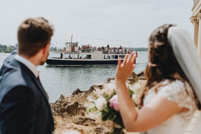 Bride and groom waving at passing boat