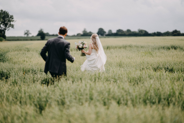 Bride and groom walking through a field