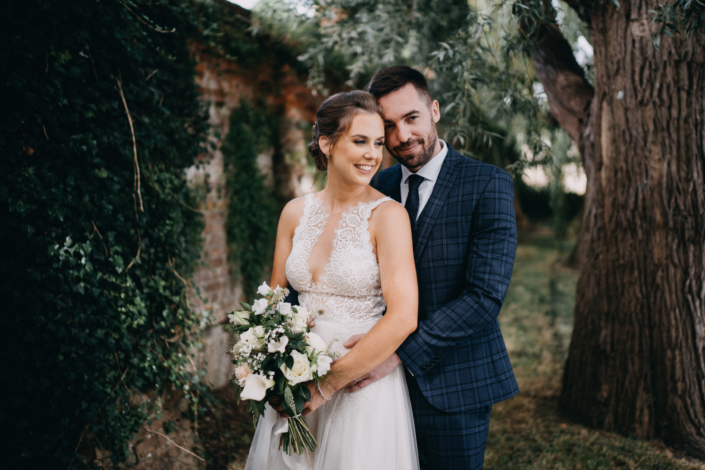 Bride and groom embracing in garden setting