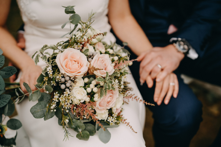 Bride holding bouquet with groom holding hands