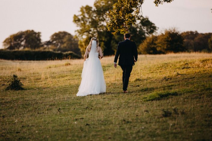 Bride and groom walking in scenic meadow