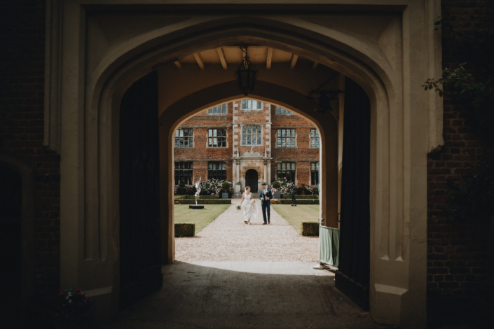 Bride and groom walking through historic archway