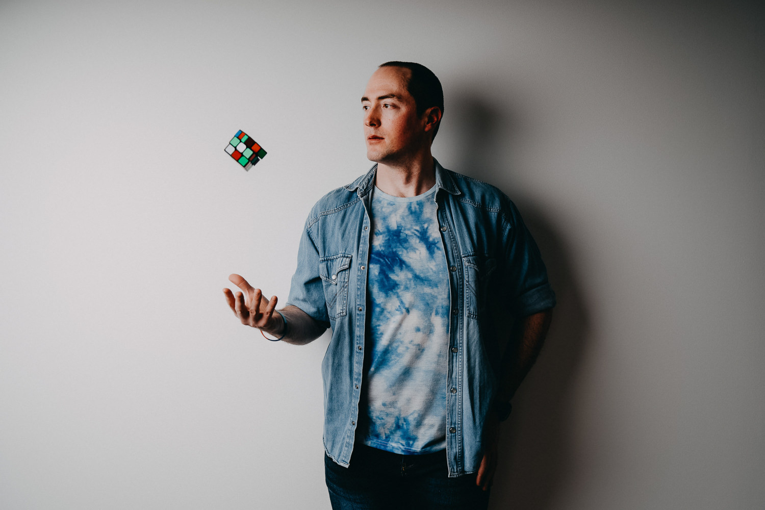 Man juggling Rubik's cube against plain background