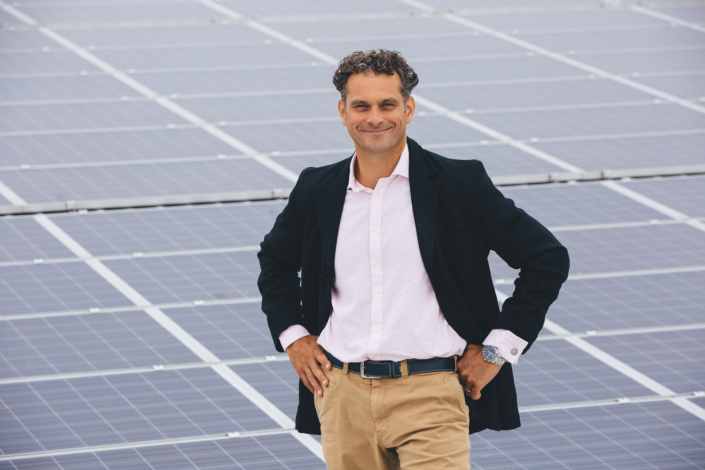 Man standing confidently on solar panel rooftop.