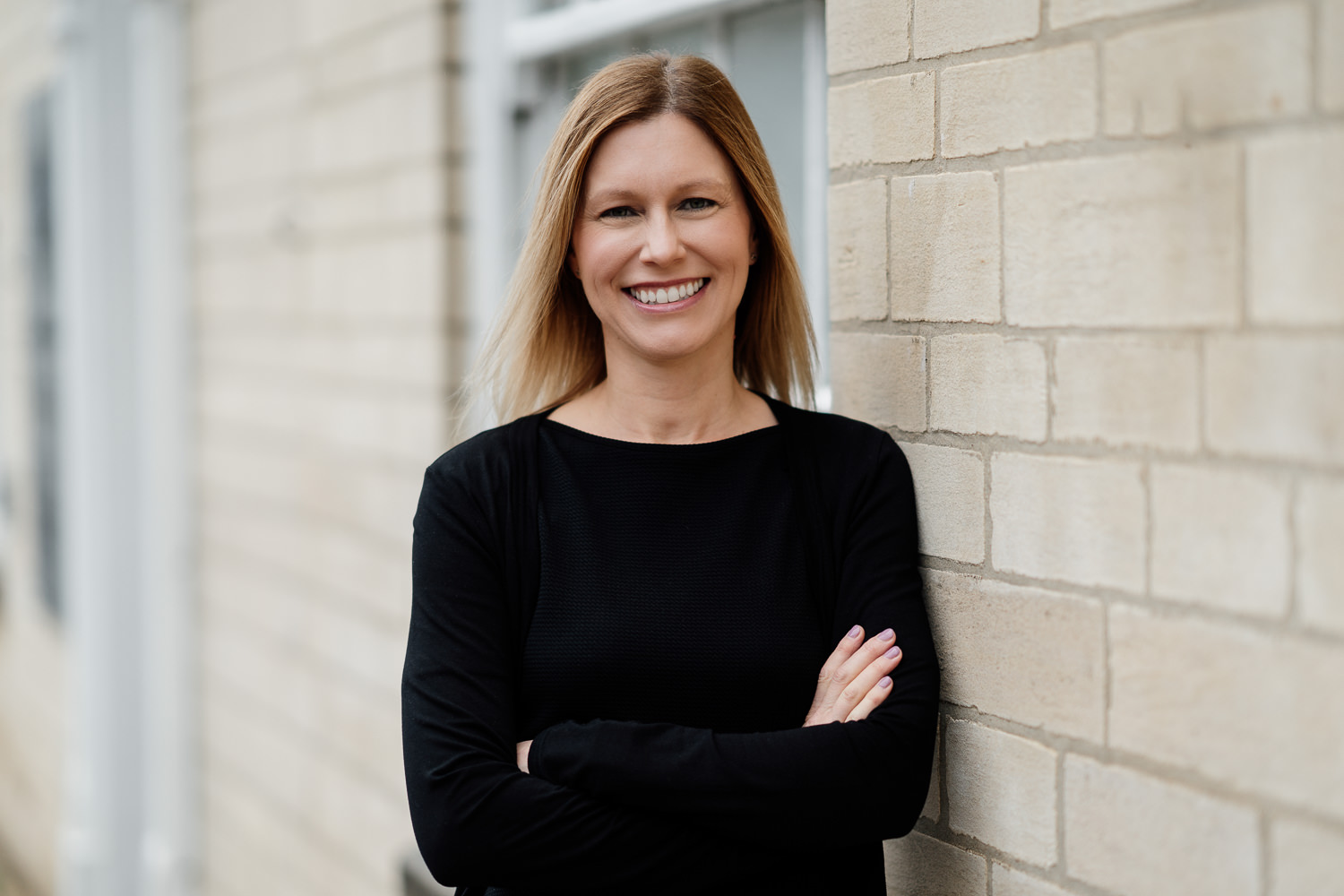 Smiling woman leaning against a brick wall