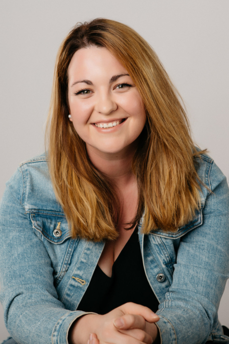 Smiling woman in denim jacket portrait.