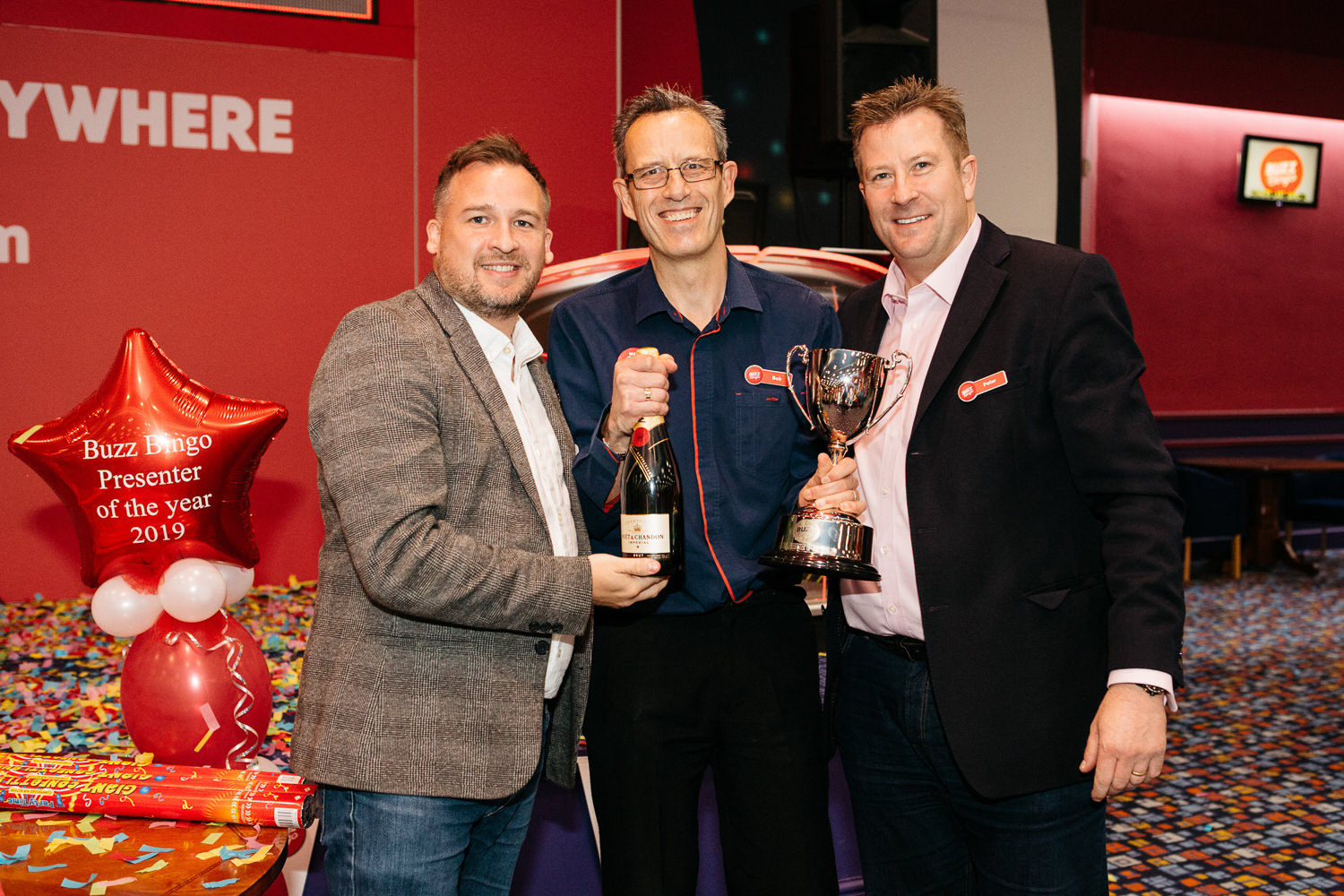Three men celebrating with trophy and champagne