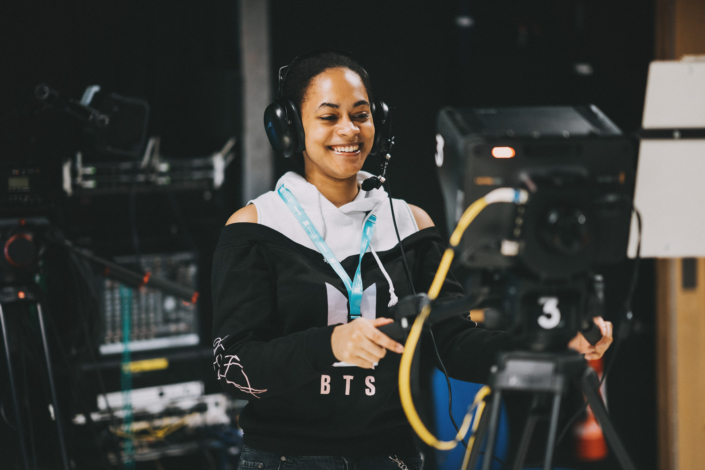 Smiling woman operating a professional video camera