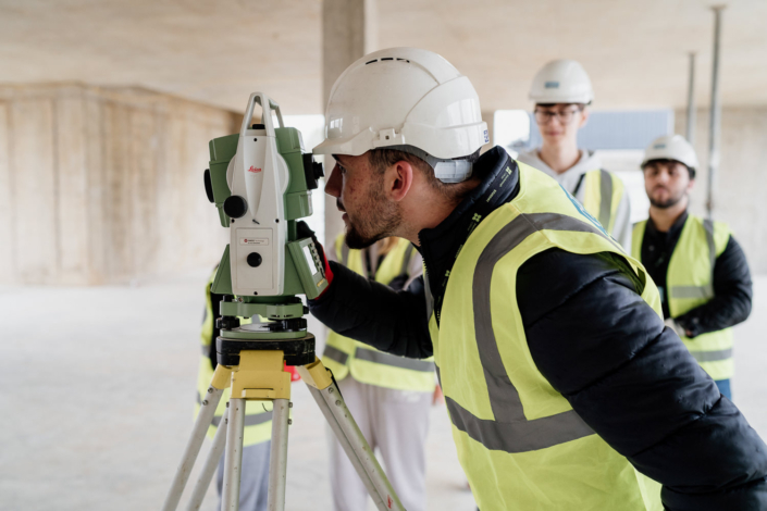 Construction workers using surveying equipment on site