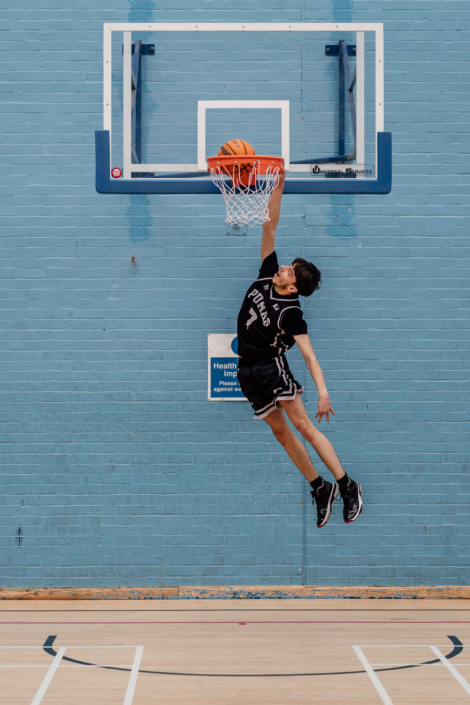 Basketball player dunking at indoor sports court.