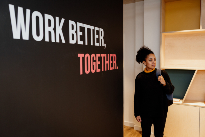 Woman standing near teamwork motivational sign