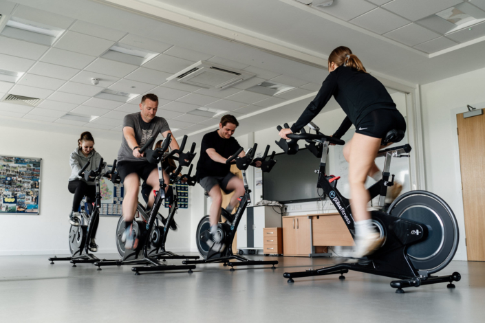 People exercising on indoor cycling bikes together.