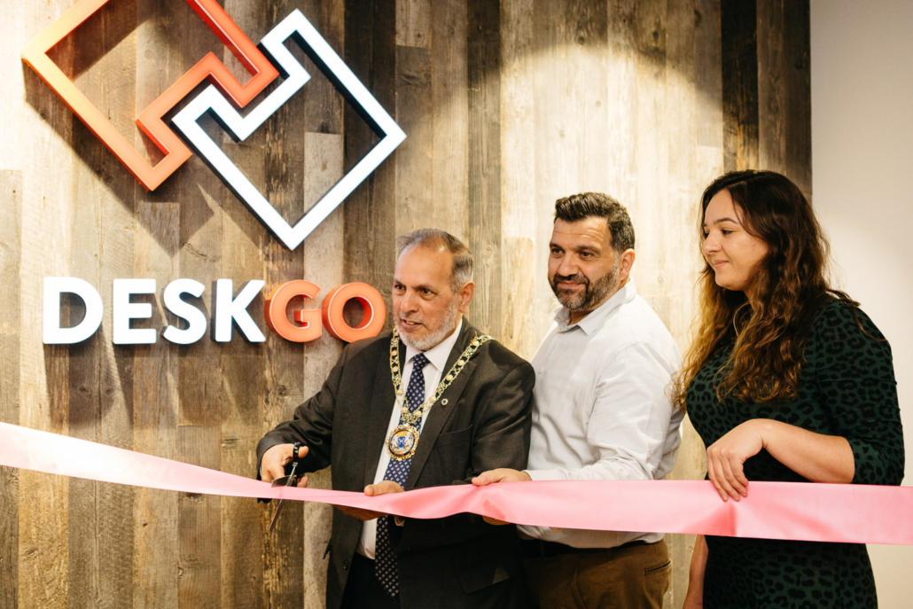 Office ribbon-cutting ceremony with three people.