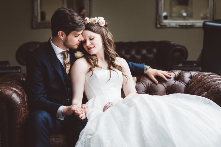 Bride and groom sitting on leather sofa