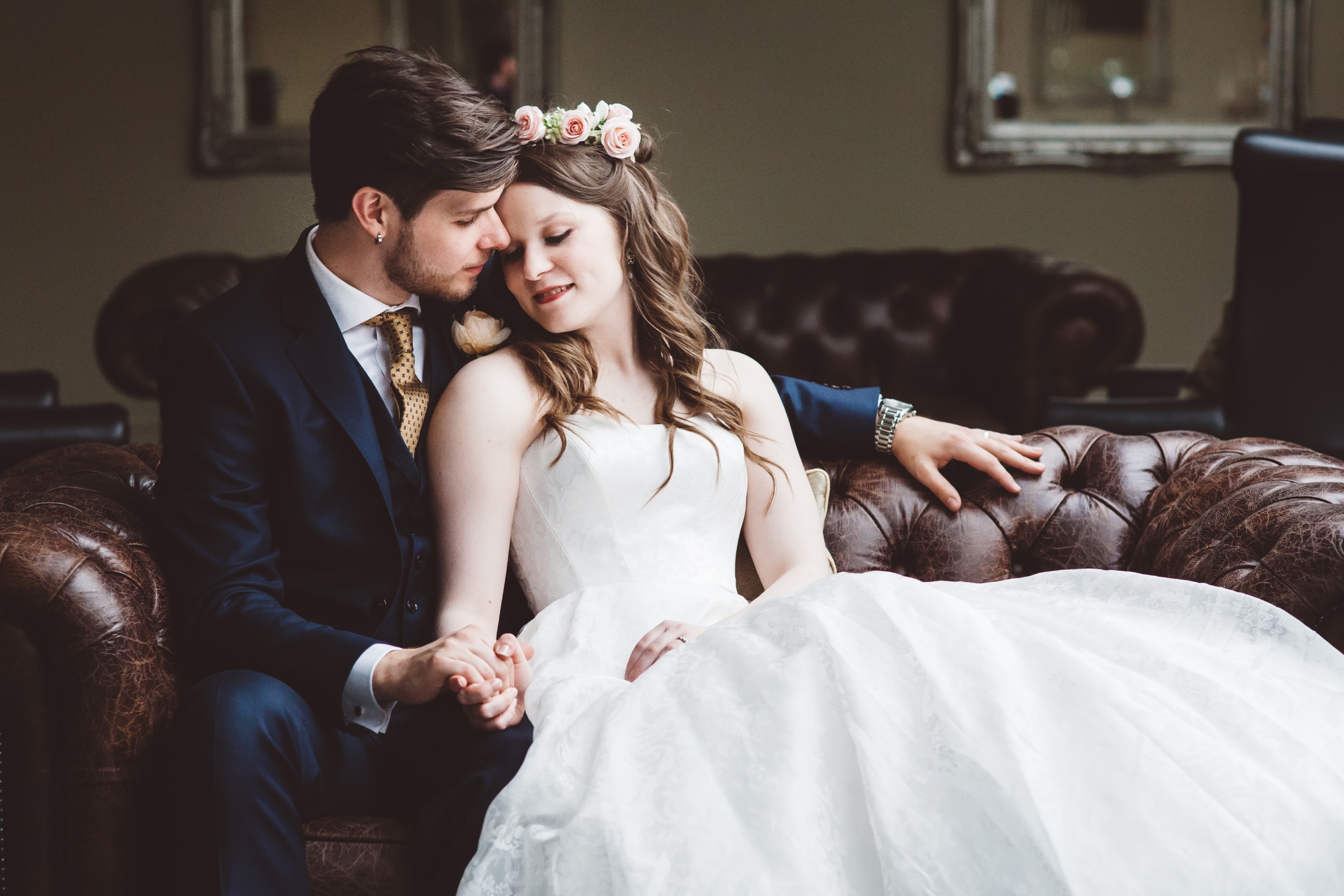 Bride and groom sitting on leather sofa