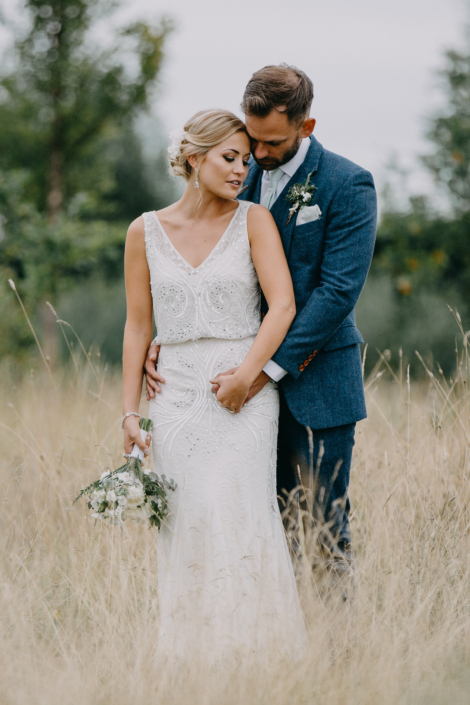 Bride and groom embracing in a field